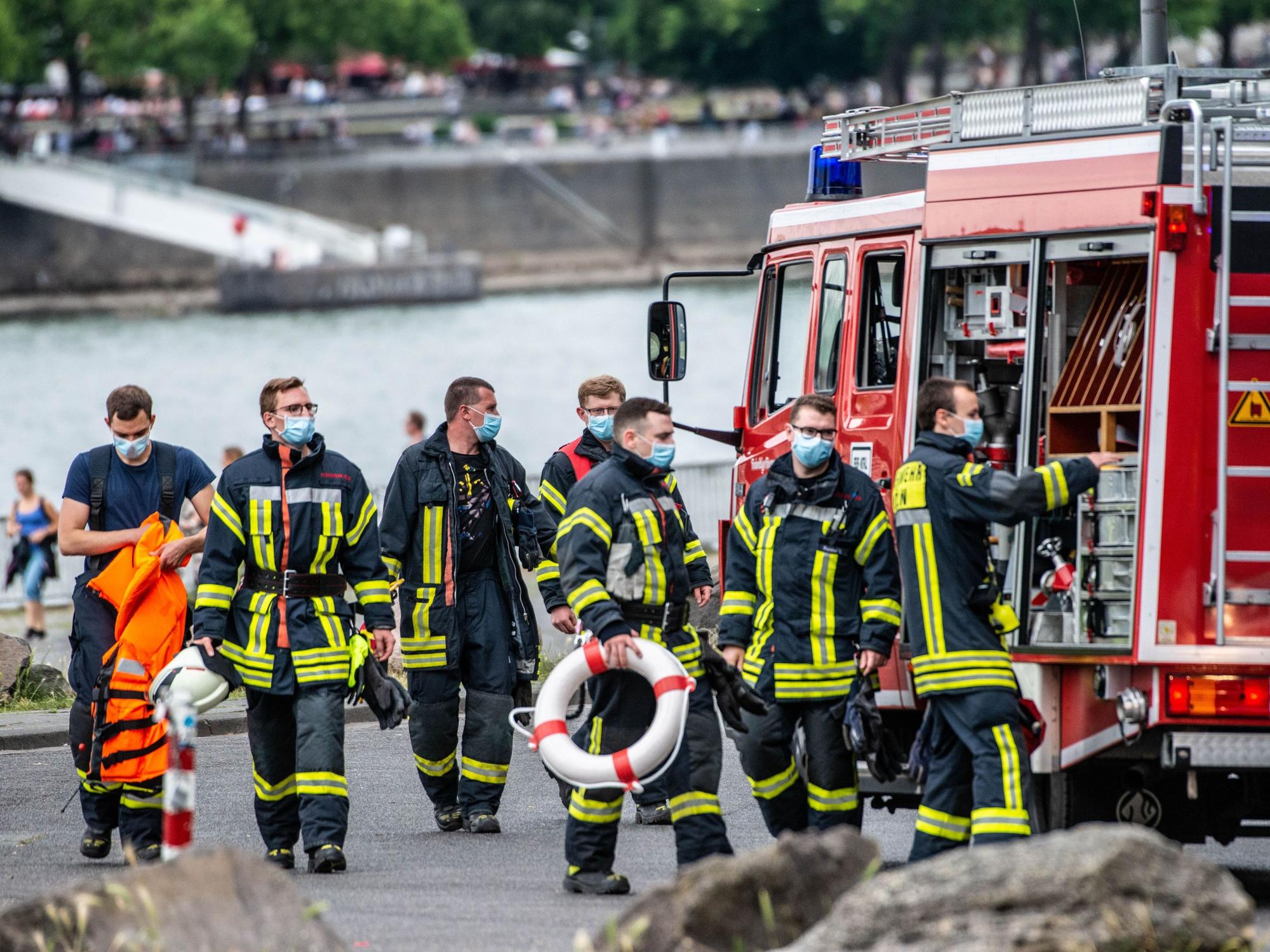 Feuerwehrmänner stehen am Rhein.
