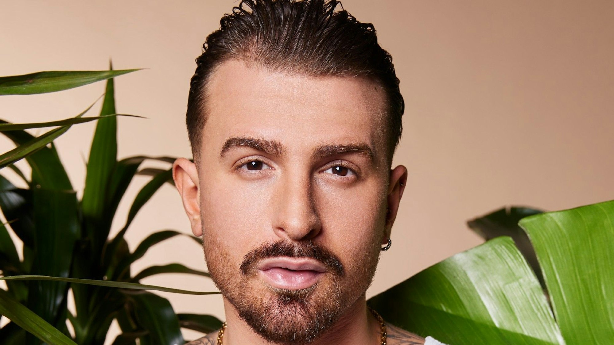 Gigi Birofio posiert hinter mehreren Pflanzen.