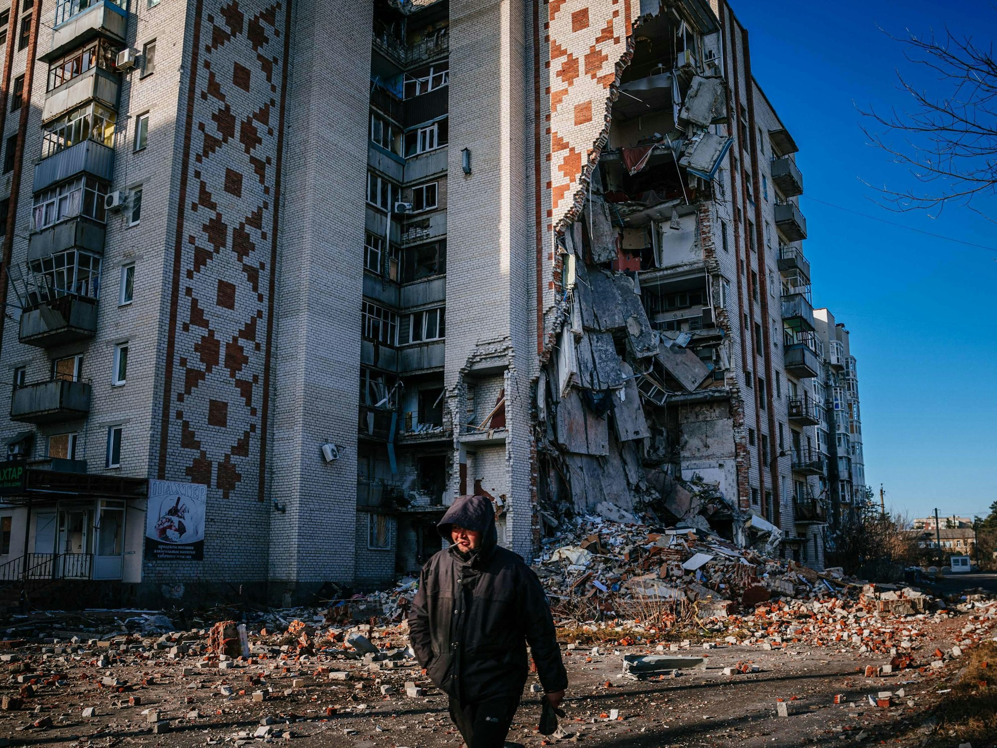 TOPSHOT - A man walks by a destroyed residential building in the city of Lyman, Donetsk region on January 4, 2023, amid the Russian invasion of Ukraine. (Photo by Dimitar DILKOFF / AFP)