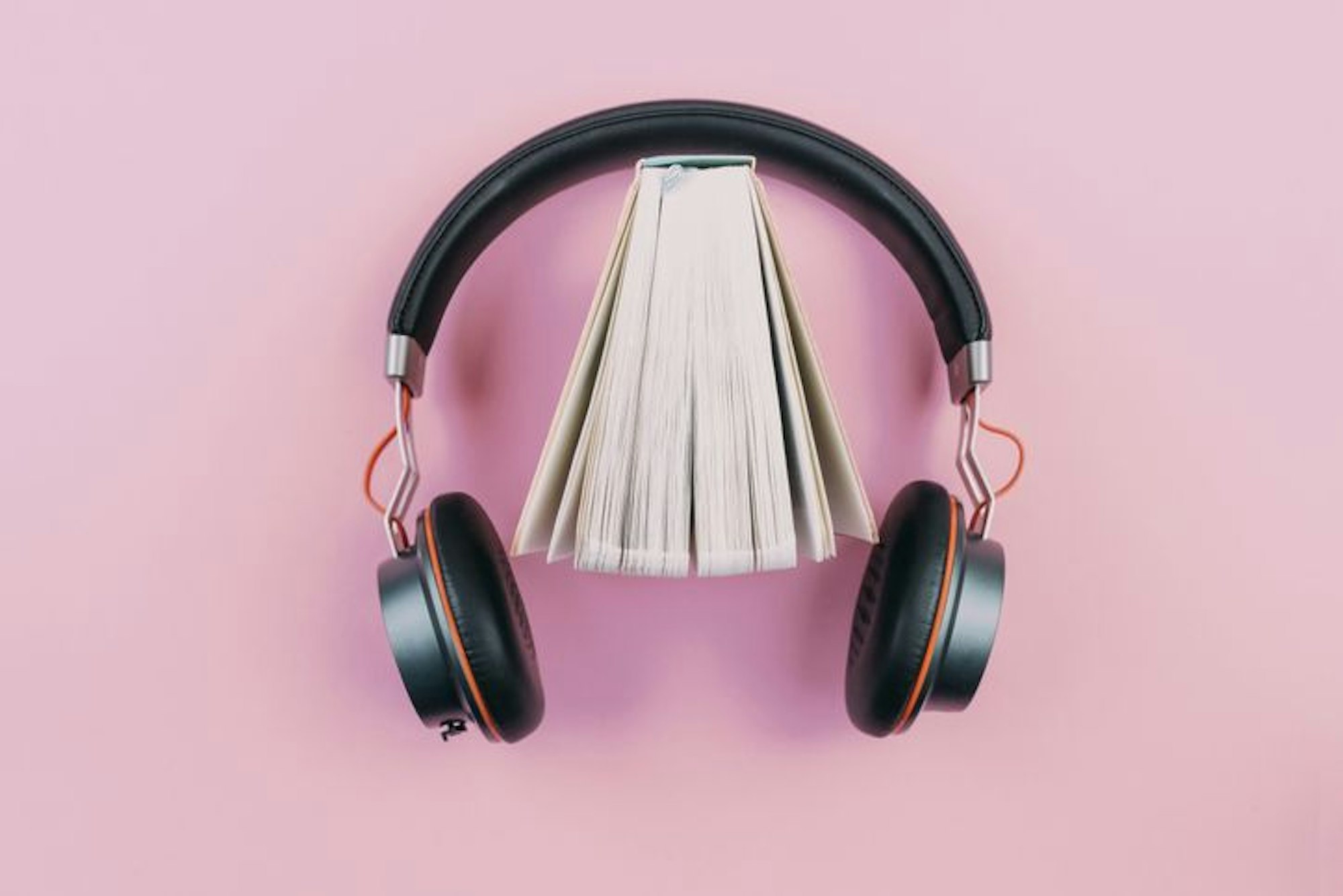Buch und Kopfhörer auf pinkem Hintergrund
