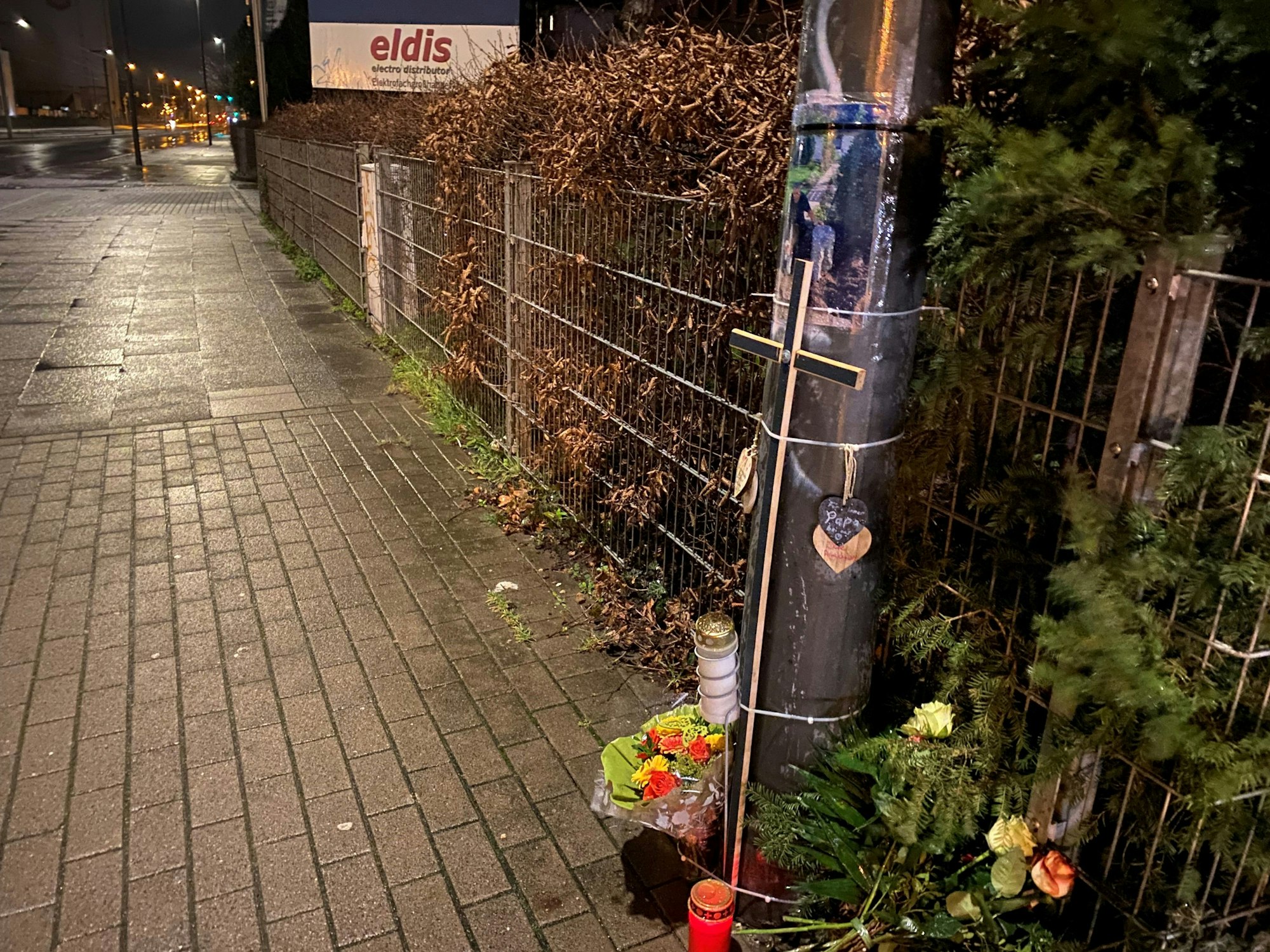 Blumen, Kerzen und Fotos liegen an einer Unfallstelle.