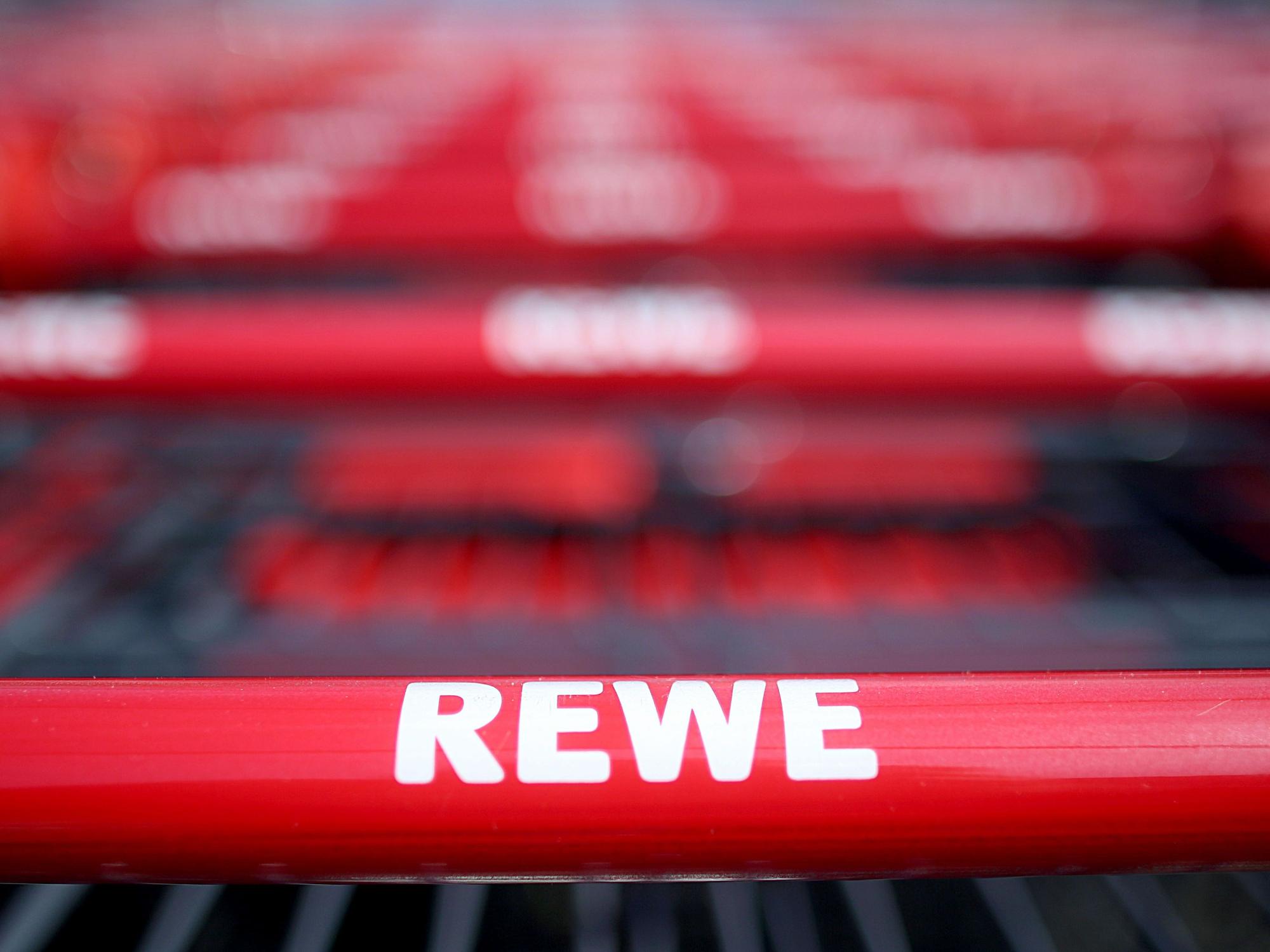 Einkaufswagen stehen vor einem Rewe-Supermarkt in Köln.