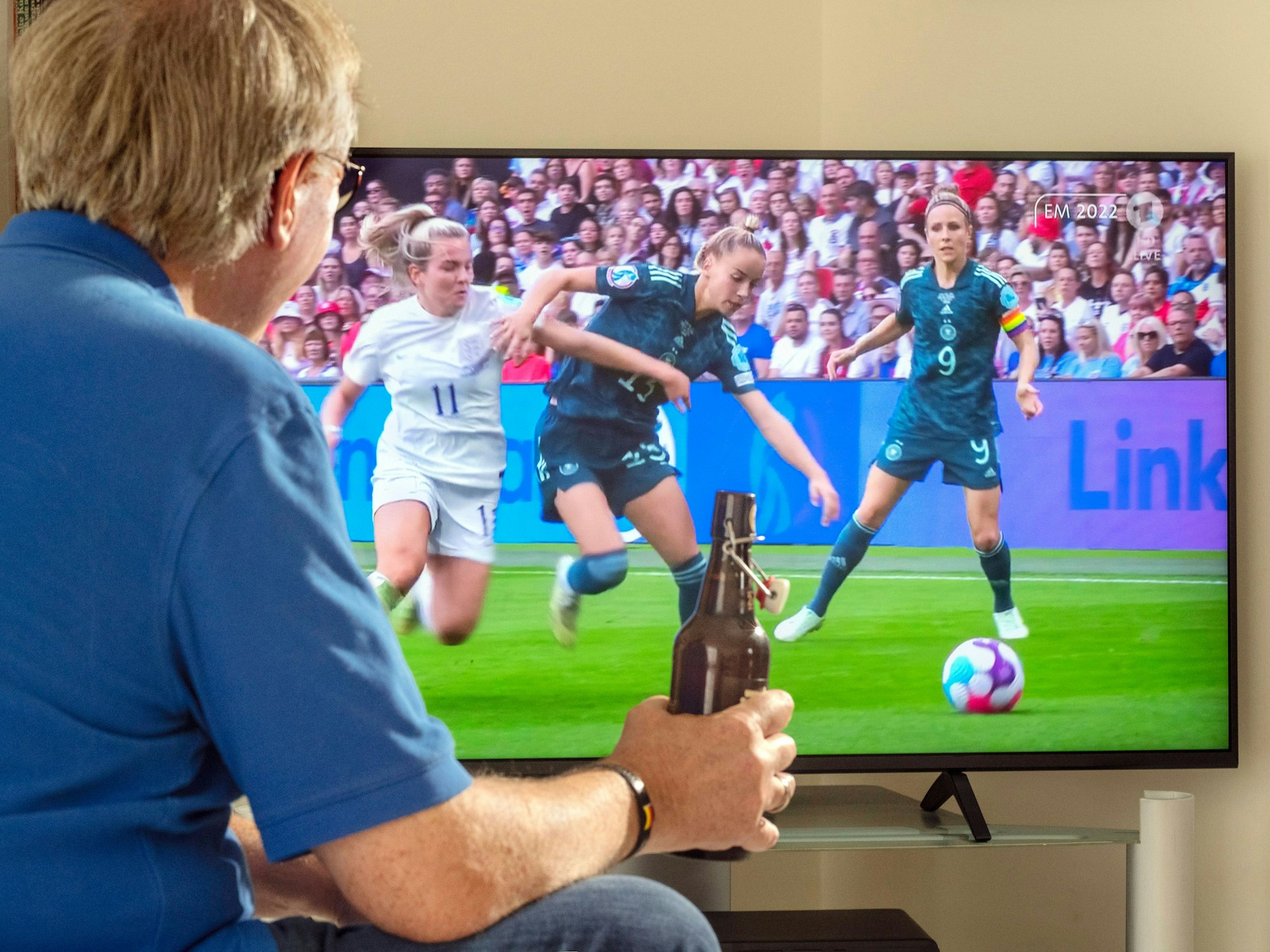 Ein Mann schaut live das Finale der Frauen Fussball-EM vor dem Fernseher.