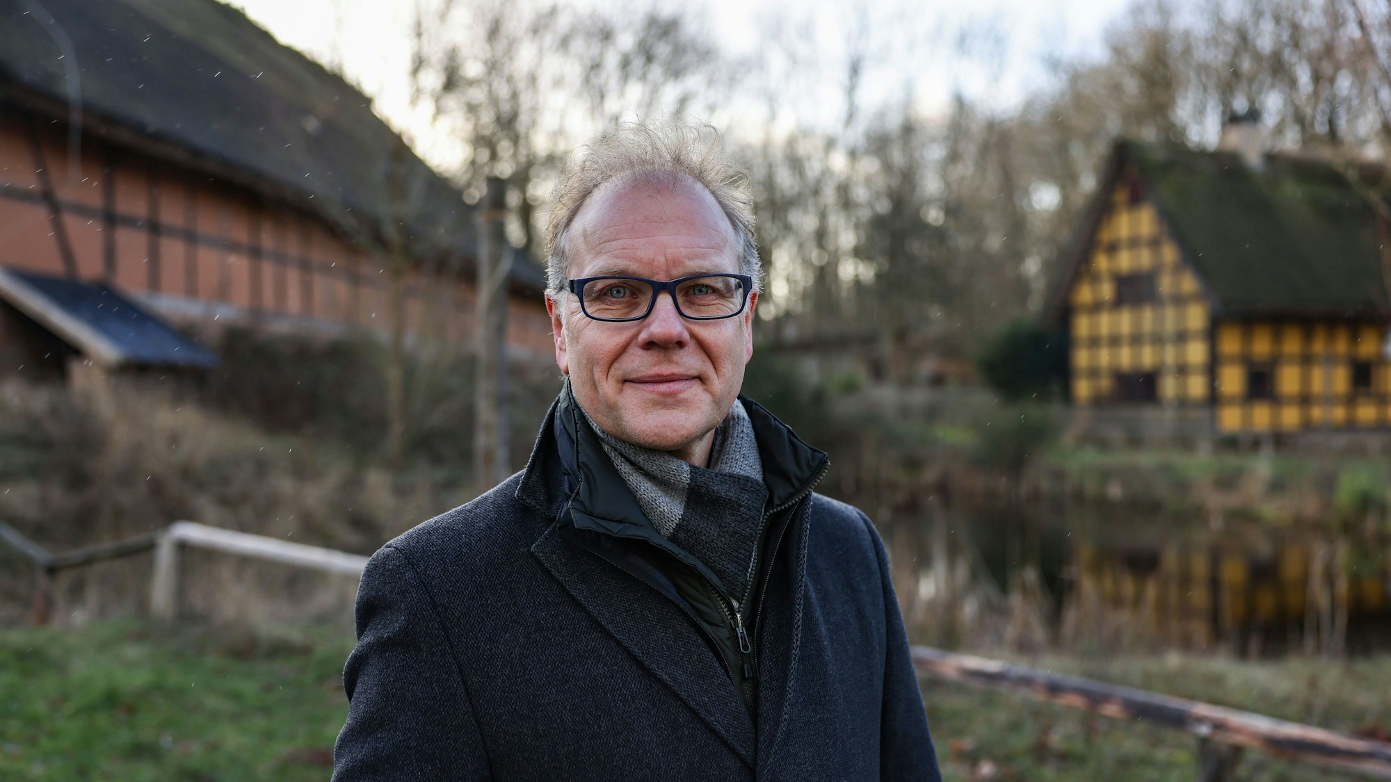 Carsten Vorwig, Museumsdirektor im Freilichtmuseum Kommern, steht vor Fachwerkhäusern.
