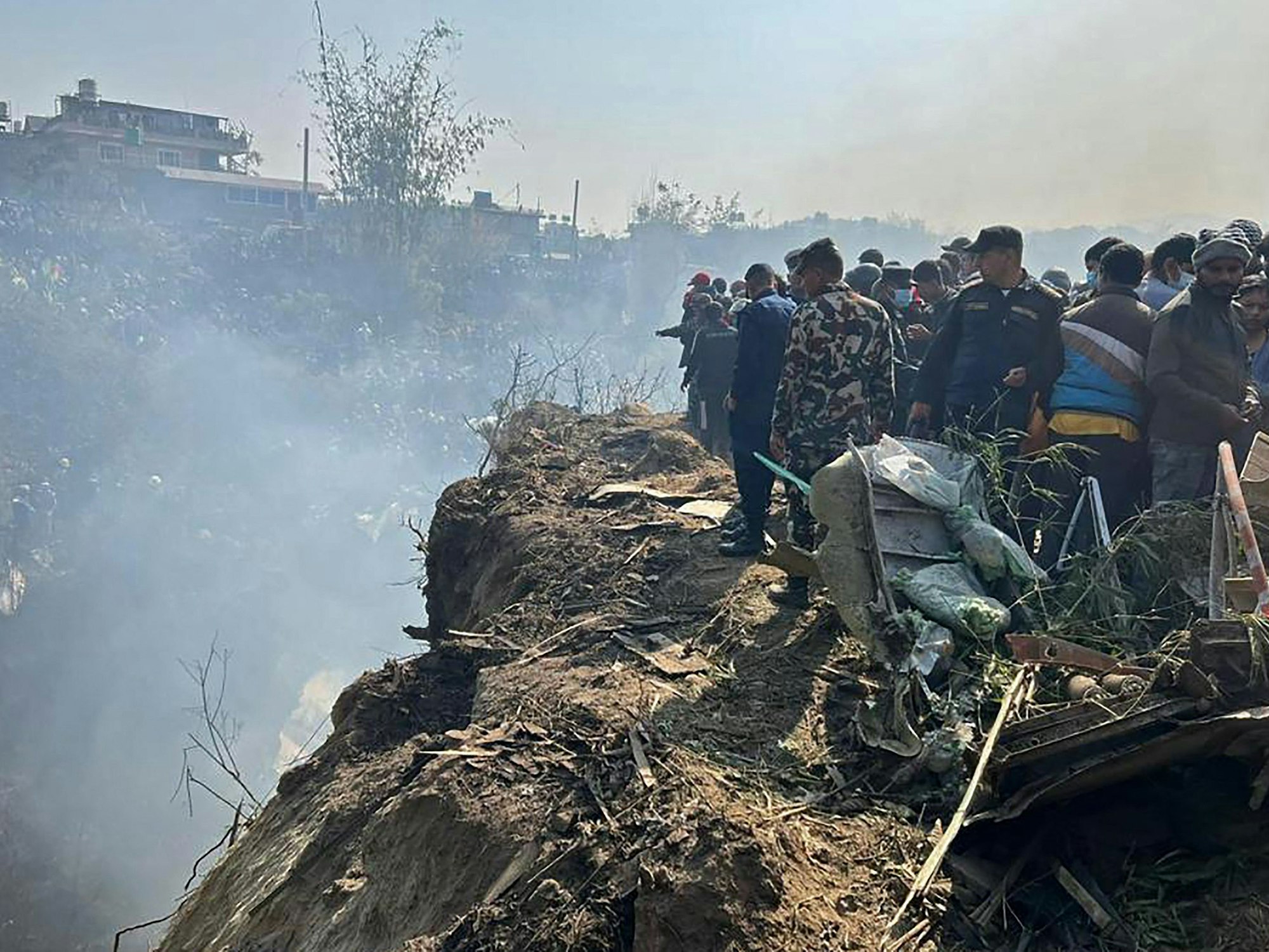 Menschen stehen an der Stelle, an der am 15. Januar 2023 in Pokhara, Nepal ein Passagierflugzeug abgestürzt ist.