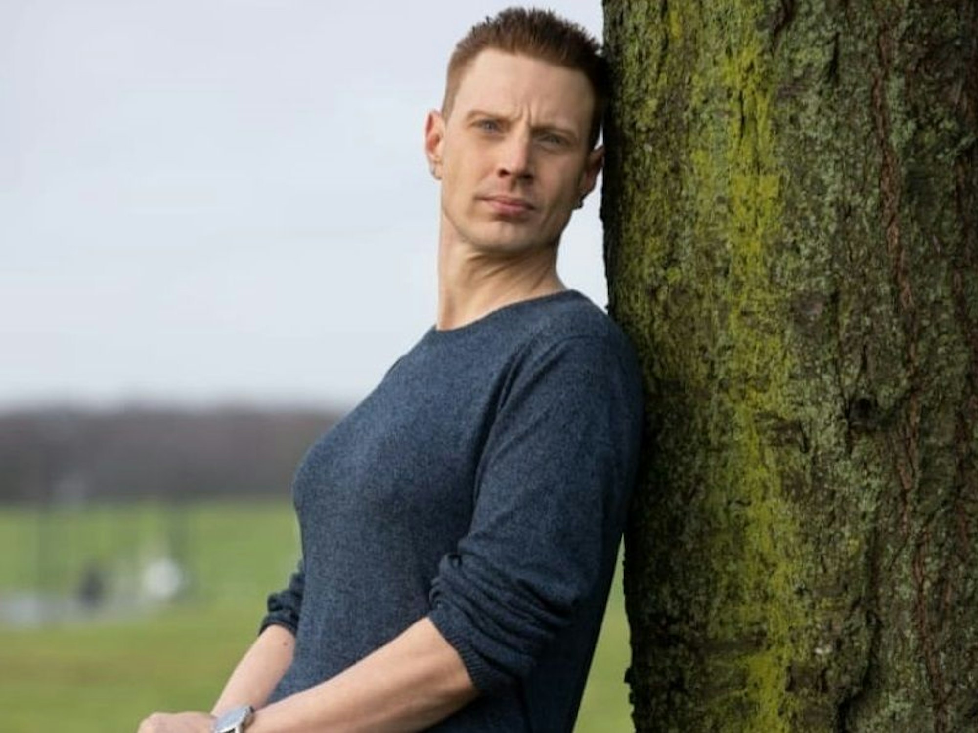 Marc Dominik Rosenzweig wollte eine Frau sein. Hier lehnt er als Mann, aber mit Brust, an einem Baum.