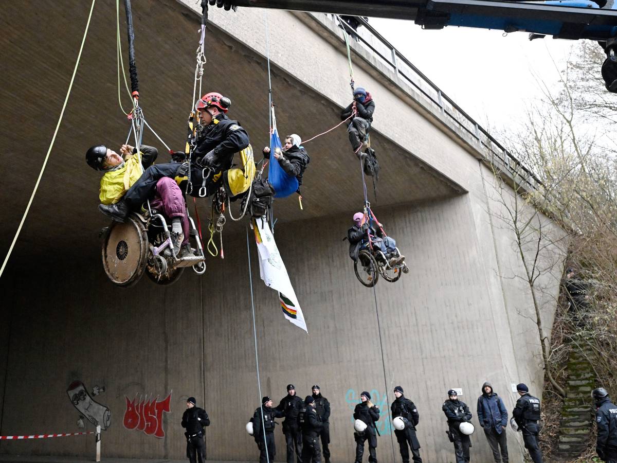 Ein Höhenretter der Polizei hilft einem Umweltaktivisten im Rollstuhl auf den Boden.