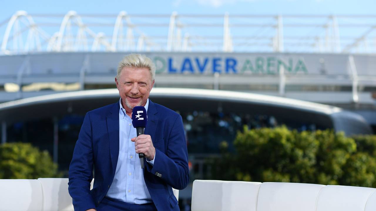 Boris Becker sitzt mit einem Eurosport-Mikrofon in der Hand auf einem Sofa.