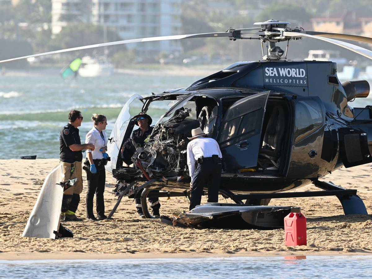 Mitarbeiter der Polizei, der Feuerwehr und des Rettungsdienstes, hier im Januar 2023, inspizieren einen Sea-World-Hubschrauber am Ort einer Hubschrauber-Kollision in der Nähe von Seaworld. An der australischen Gold Coast sind zwei Hubschrauber in der Luft kollidiert.