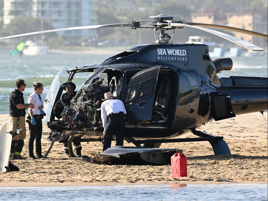 Mitarbeiter der Polizei, der Feuerwehr und des Rettungsdienstes, hier im Januar 2023, inspizieren einen Sea-World-Hubschrauber am Ort einer Hubschrauber-Kollision in der Nähe von Seaworld. An der australischen Gold Coast sind zwei Hubschrauber in der Luft kollidiert.