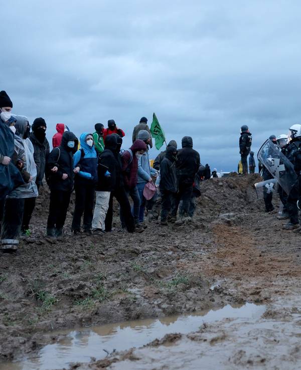 Polizisten und Demonstranten stehen sich bei der Demonstration von Klimaaktivisten am Rande des Braunkohletagebaus bei Lützerath gegenüber.