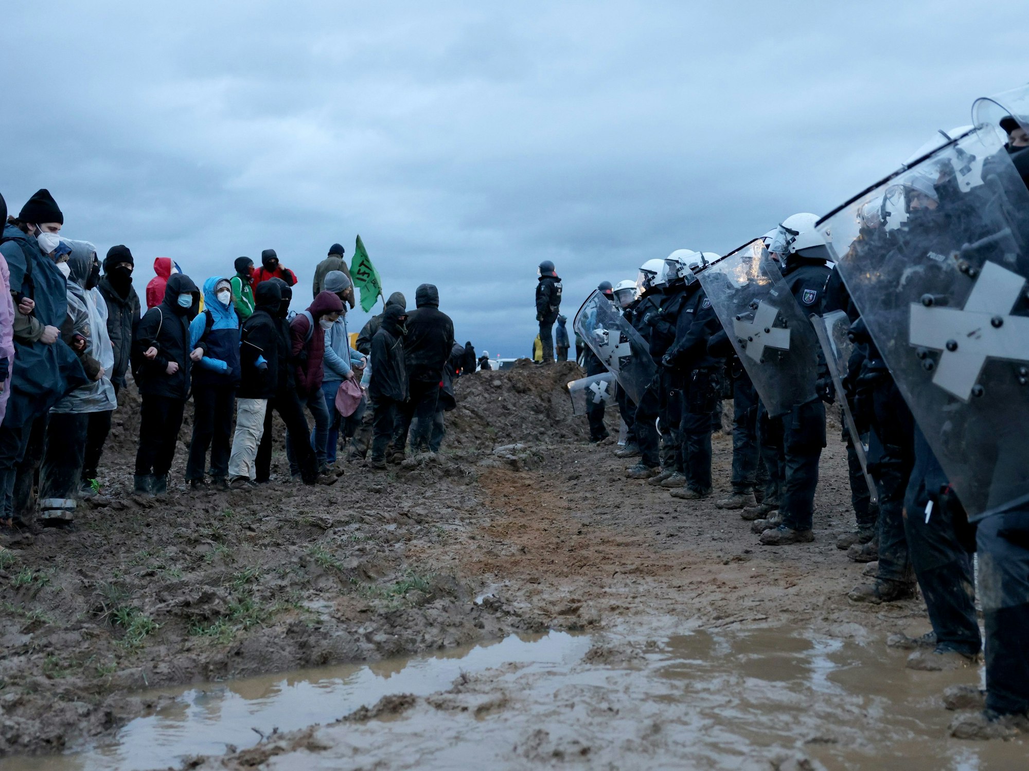 Polizisten und Demonstranten stehen sich bei der Demonstration von Klimaaktivisten am Rande des Braunkohletagebaus bei Lützerath gegenüber.