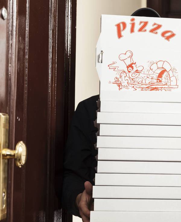 Ein Pizzabote hat einige Pizzakartons in den Händen.