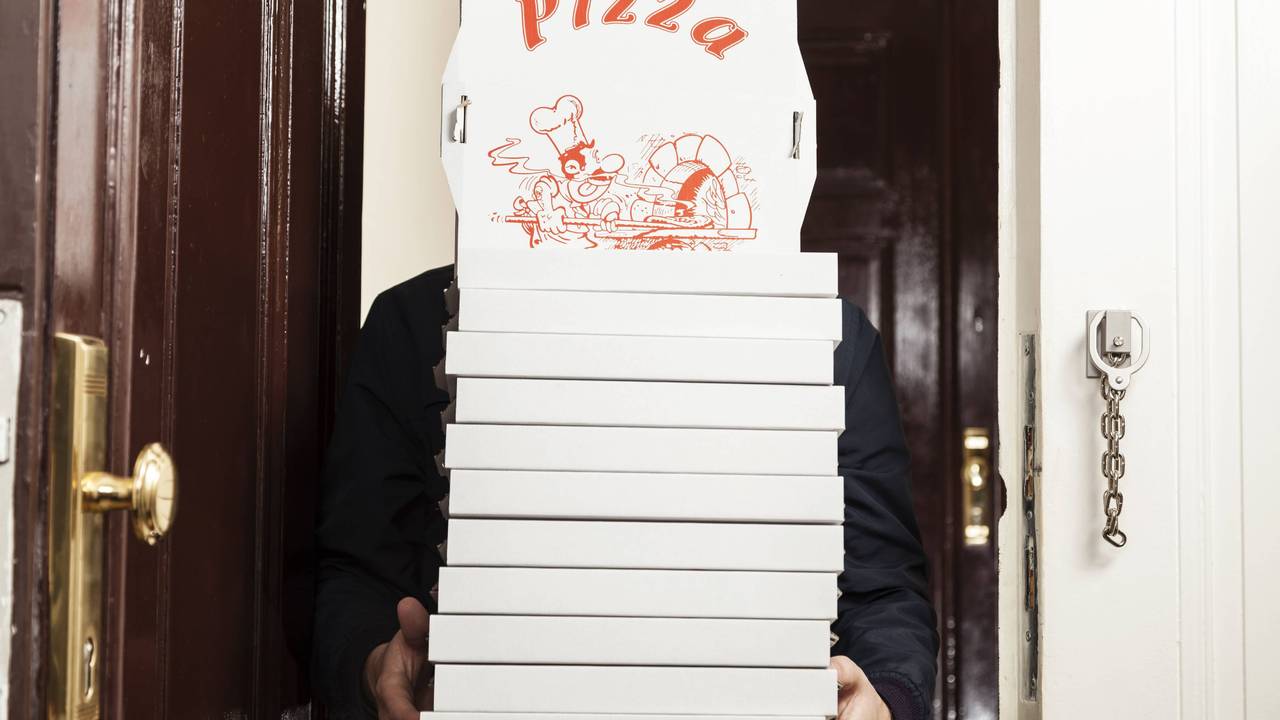 Ein Pizzabote hat einige Pizzakartons in den Händen.