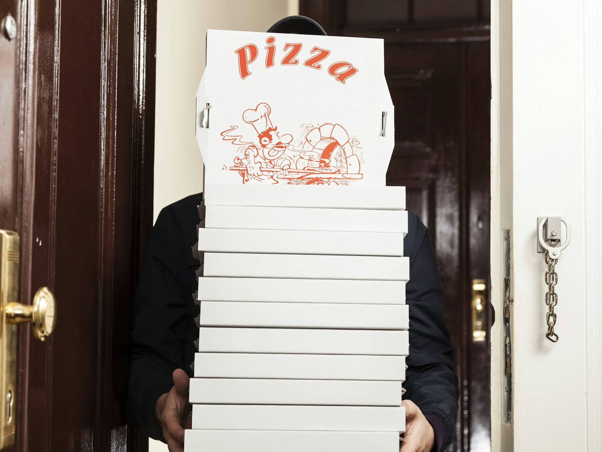 Ein Pizzabote hat einige Pizzakartons in den Händen.