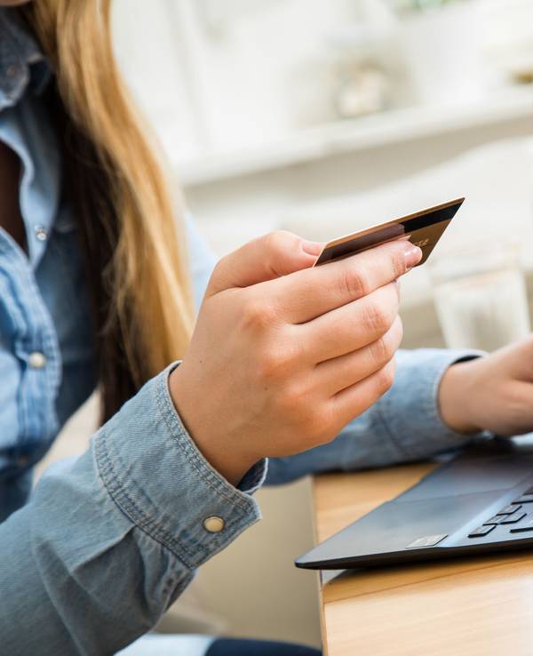 Eine Frau, hier im Oktober 202 in Wittenberge, tippt die Nummer ihrer Kreditkarte in ein Laptop. Ein großer Online-Händler führt noch in diesem Jahr Neuerungen bei Bestellungen auf dessen Website ein.