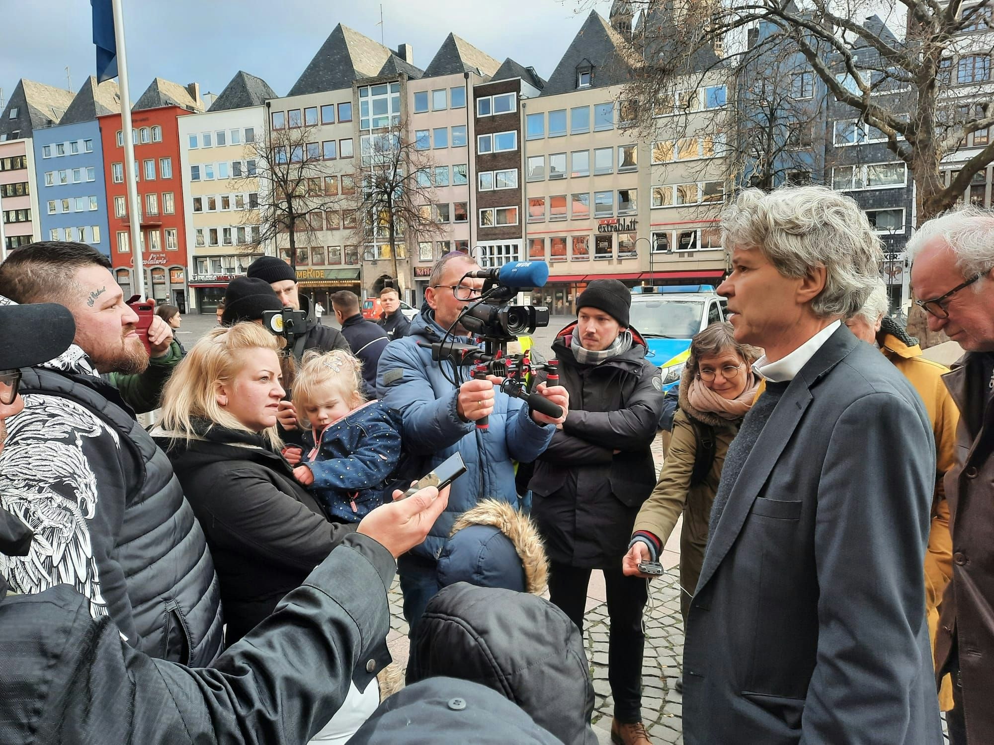 Menschen stehen vor dem Kölner Rathaus um Harald Rau herum.