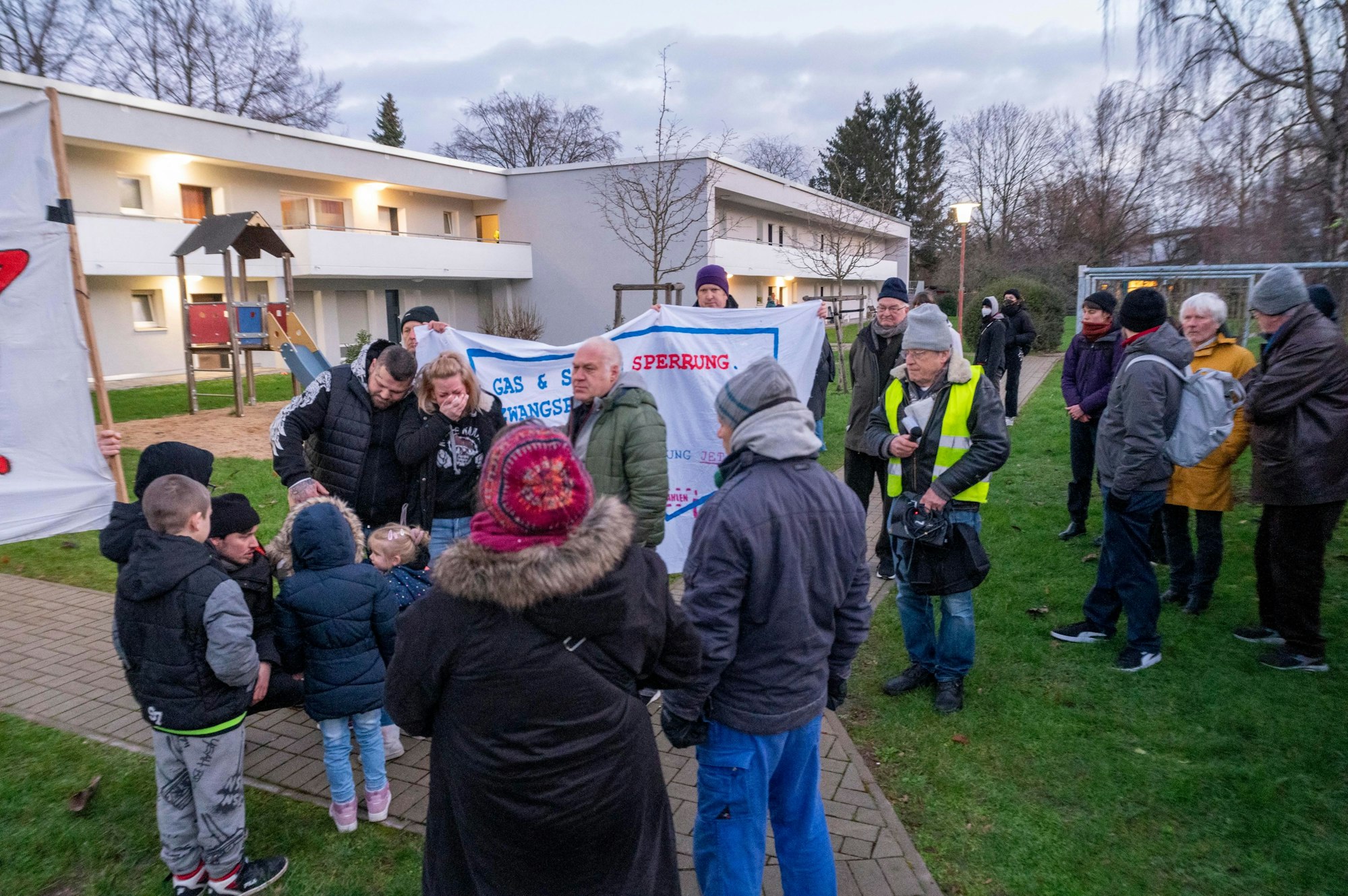 Menschen stehen bei einer Demo in einem Garten.