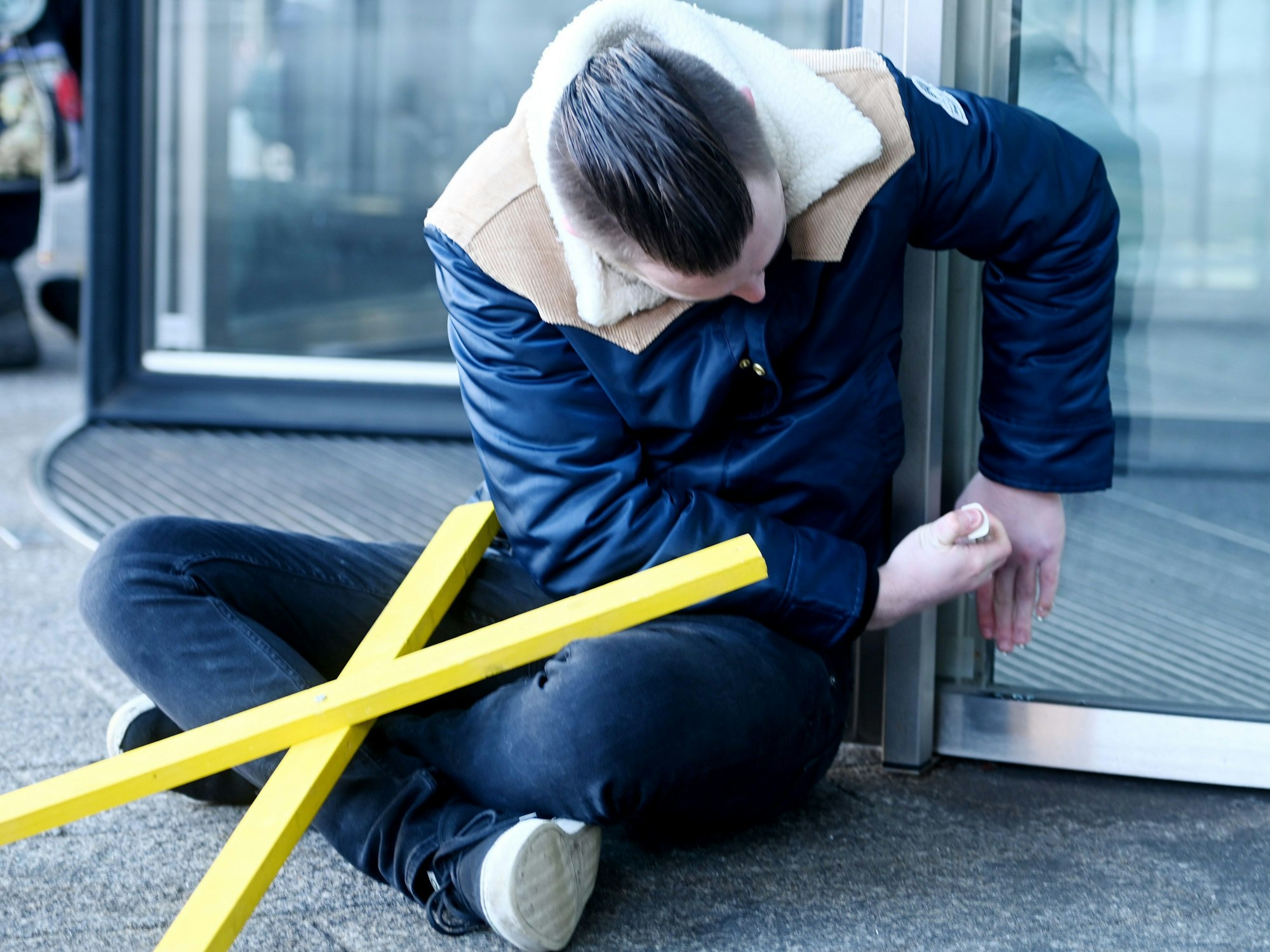 Ein Demonstrant klebt sich an der Glastür des Haupteingangs des Innenministeriums in Düsseldorf fest als Protest nach der Räumung von Lützerath.