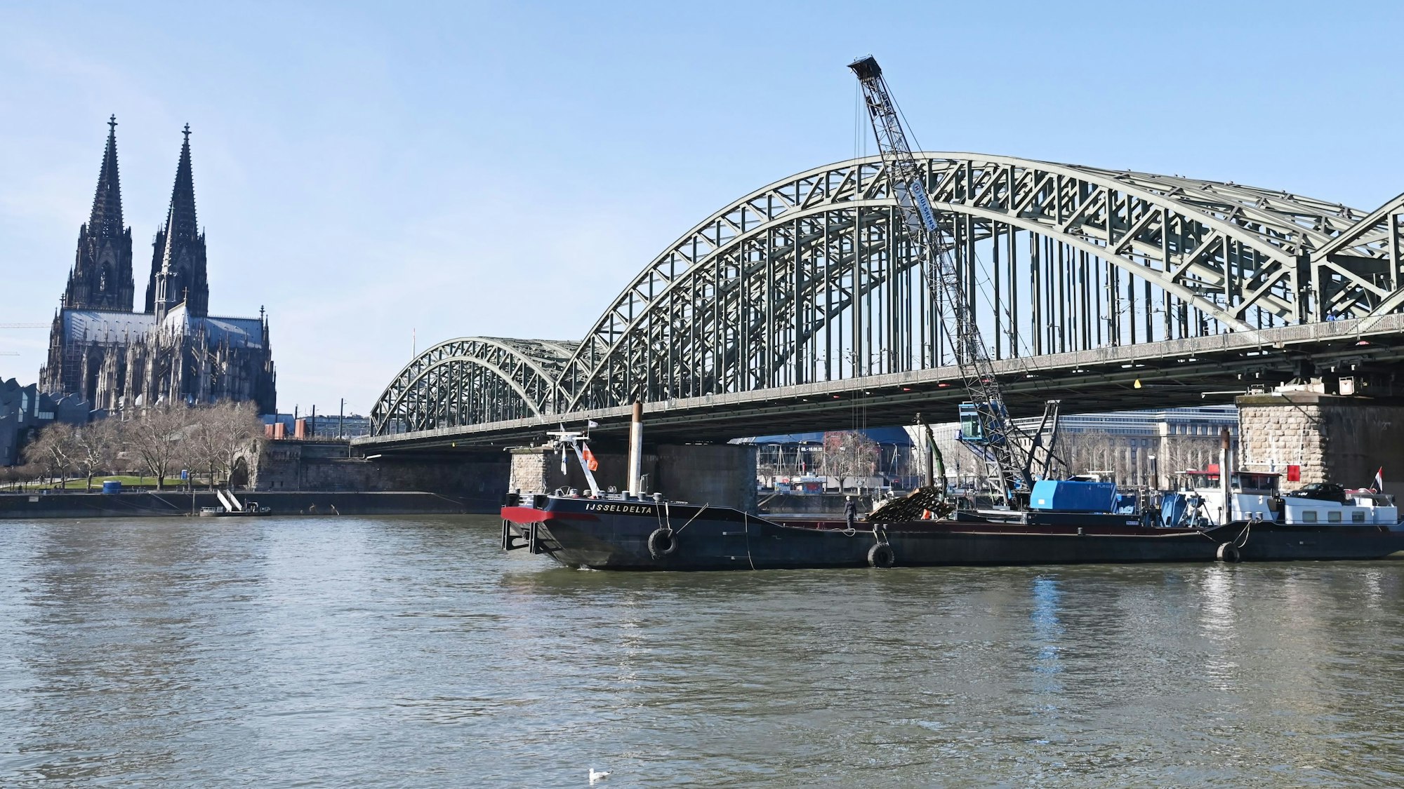 Die Hohenzollernbrücke soll verbreitert werden.
Zwei Arbeitsschiffe liegen an einem der Pfeiler.
