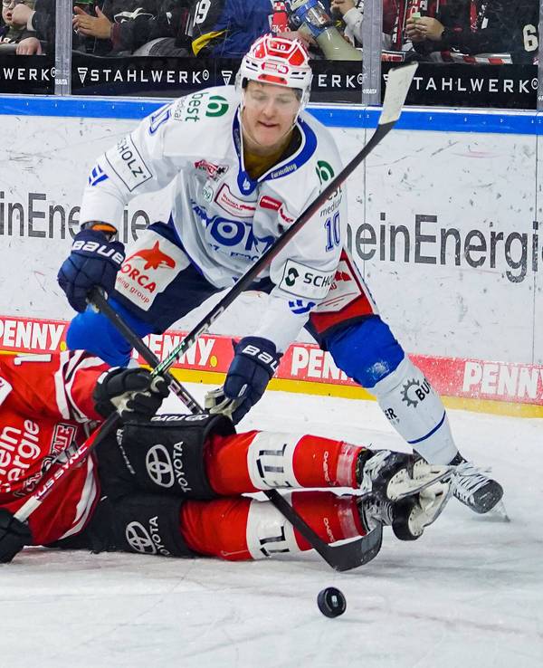 Jon Matsumoto liegt am Boden und kämpft mit Schwenningens Peter Stpornberger um den Puck.