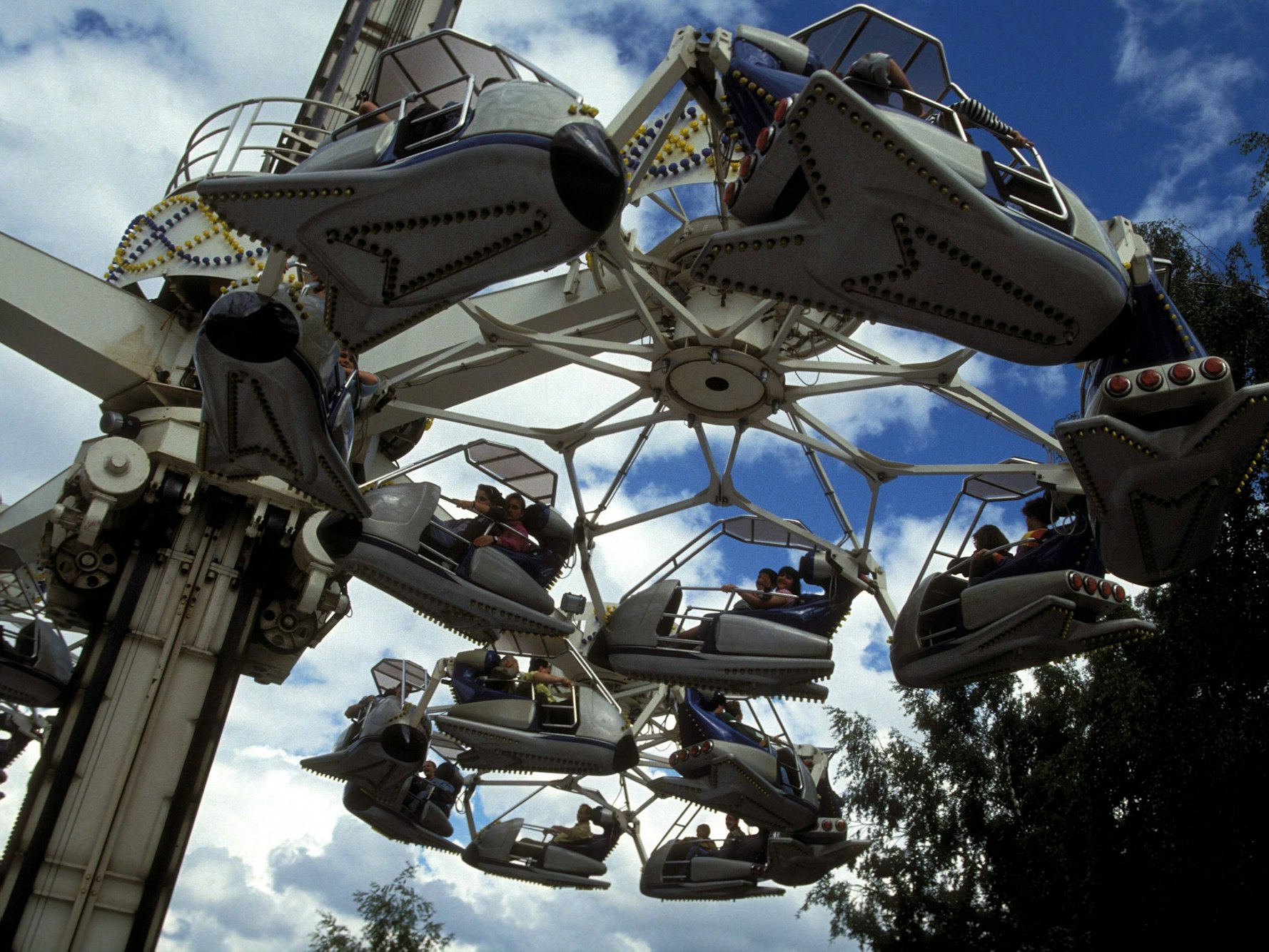 Flugzeuge der Attraktion Condor fliegen über das Phantasialand. Der Blick ist von unten auf die Flugzeuge gerichtet.