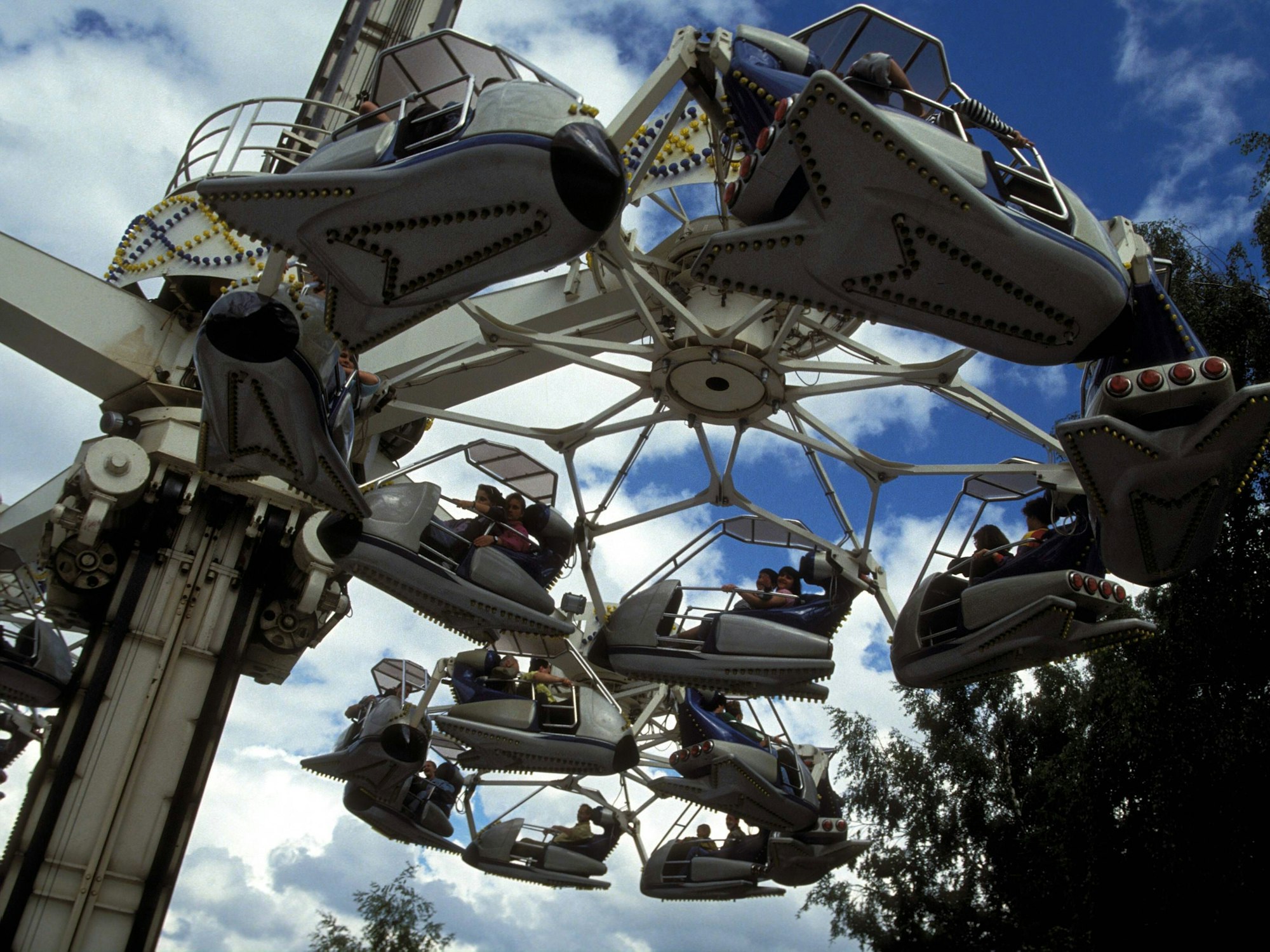 Flugzeuge der Attraktion Condor fliegen über das Phantasialand. Der Blick ist von unten auf die Flugzeuge gerichtet.