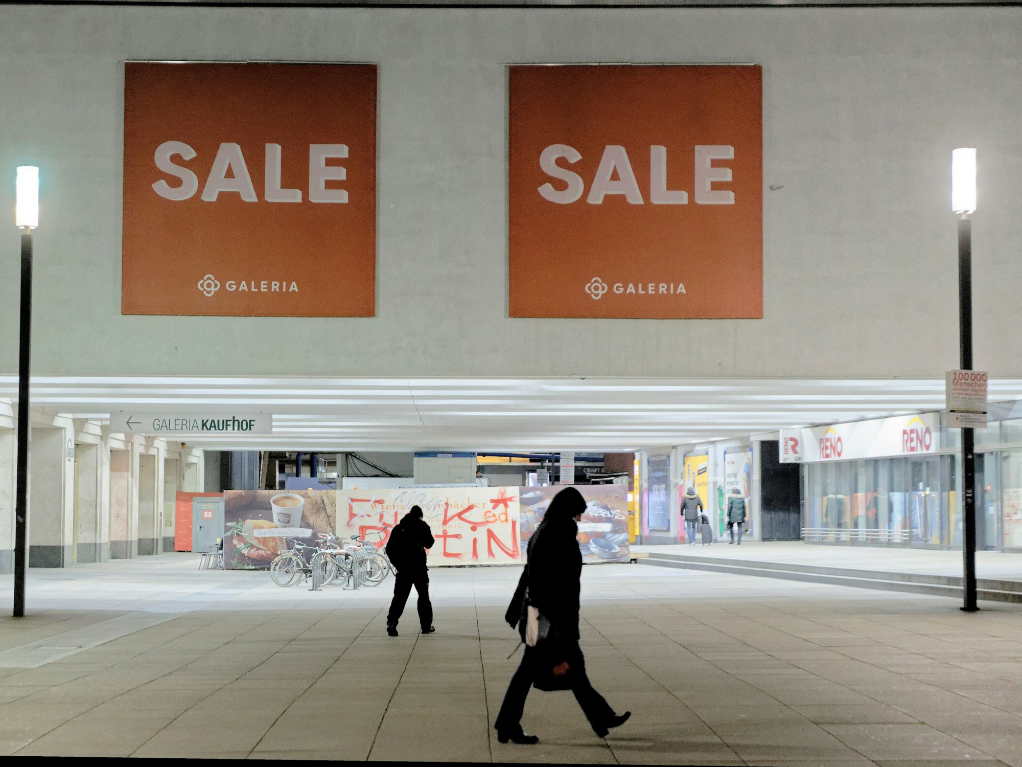 Passanten gehen gehen vor dem Galeria Kaufhof an einer Sales-Werbung vorbei.