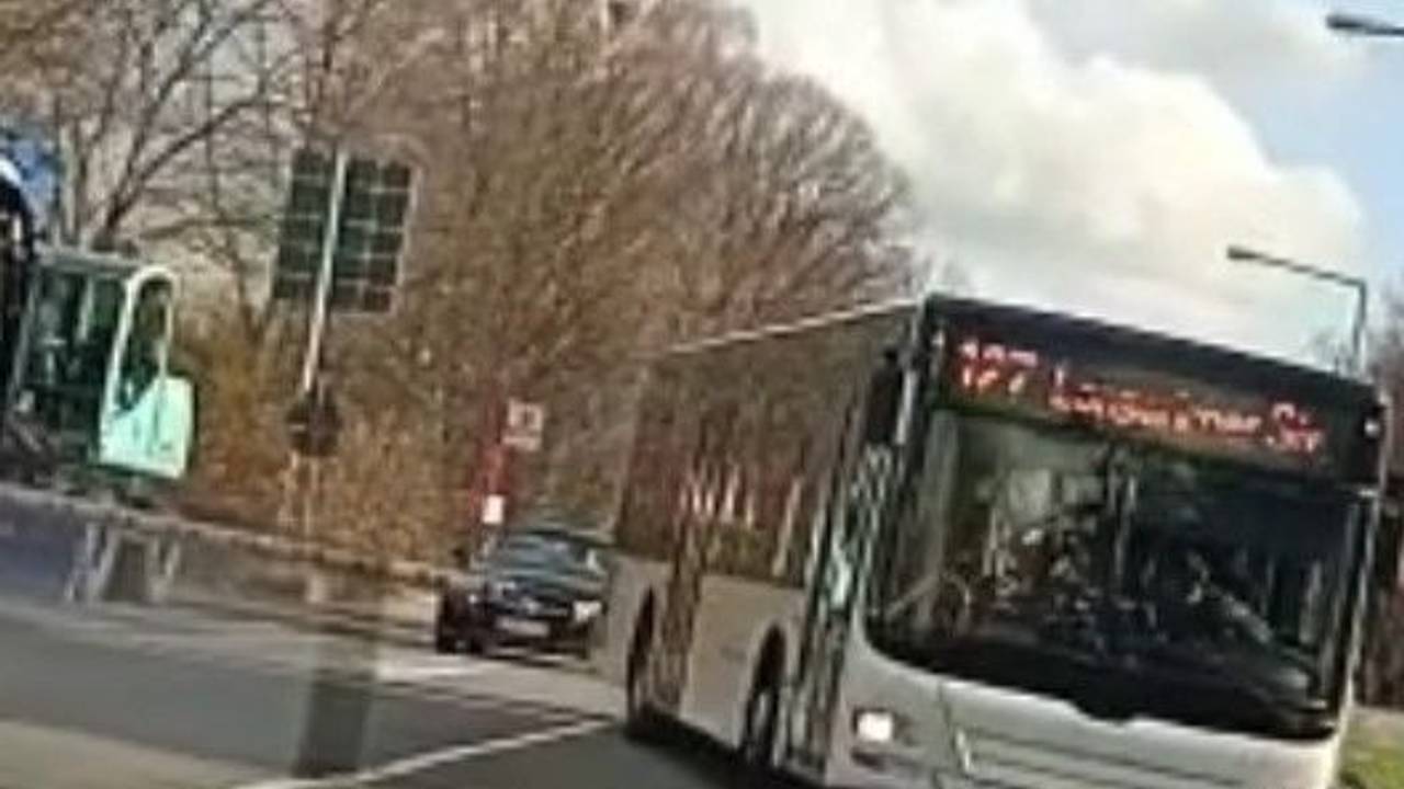 Ein Bus fährt am Bahnübergang Butzweilerstraße an der geschlossenen Halbschranke herum.