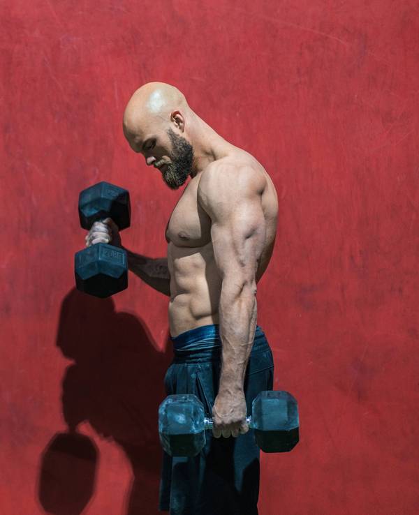 Ein Bodybuilder beim Training mit Hanteln in einem Fitnessstudio.