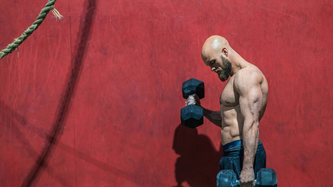 Ein Bodybuilder beim Training mit Hanteln in einem Fitnessstudio.
