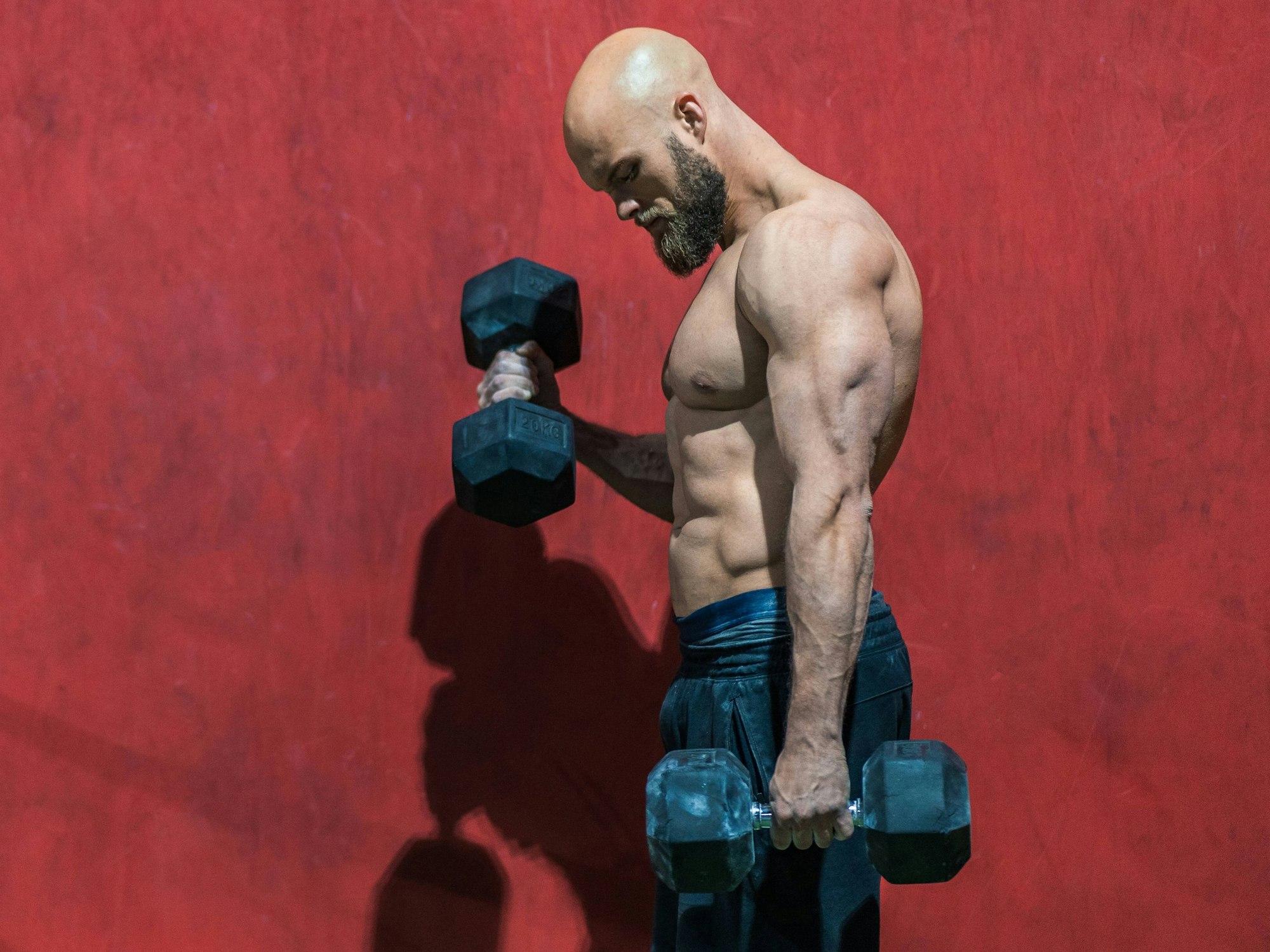 Ein Bodybuilder beim Training mit Hanteln in einem Fitnessstudio.