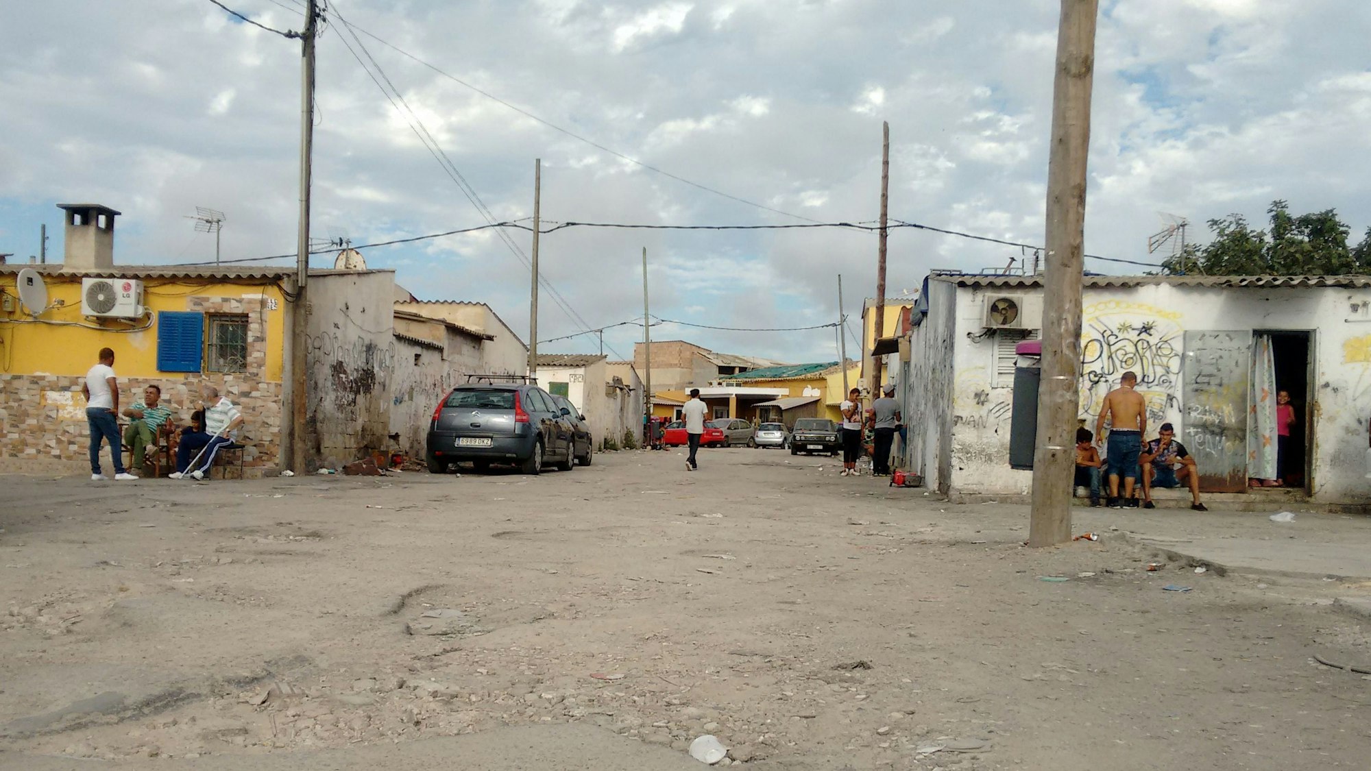 Einwohner sitzen an Gebäuden der als Drogendorf bekannten Barackensiedlung Son Riera (auch bekannt als Son Banya) unweit des Flughafens.