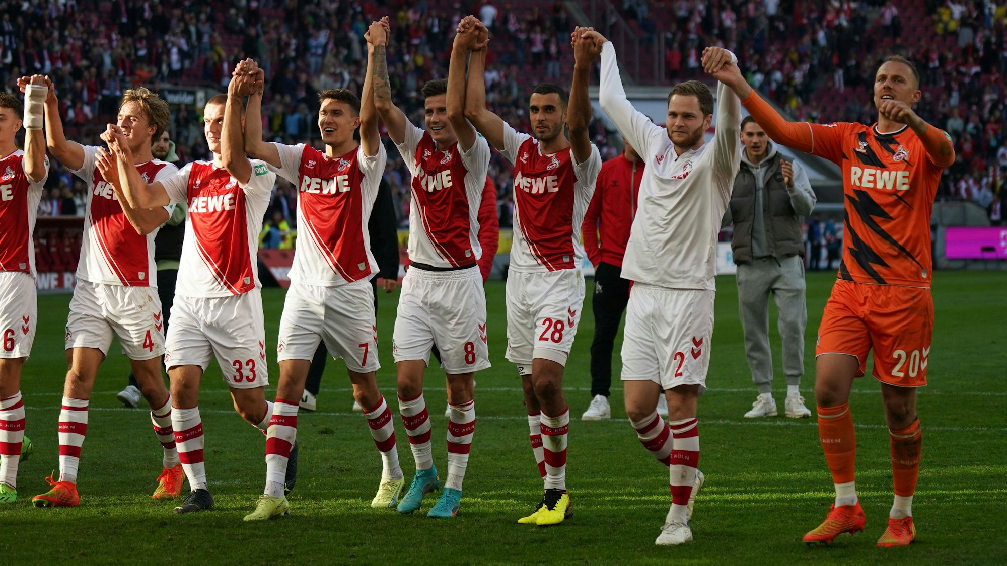 Die Spieler des 1. FC Köln jubeln vor der Südkurve.