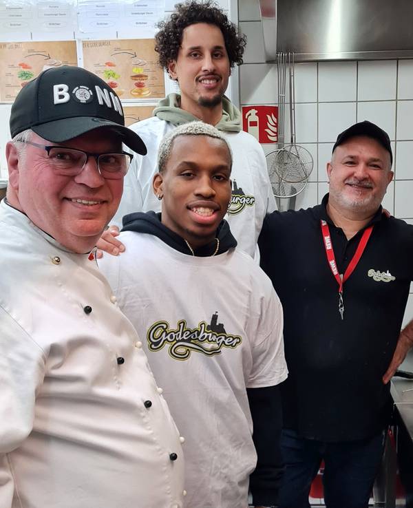 Restaurantleiter Bruno Straub, Point Guard TJ Shorts II, Center Michael Kessens und Beikoch Davut Dere-Knapp stehen in der Küche des „Godesburgers“.