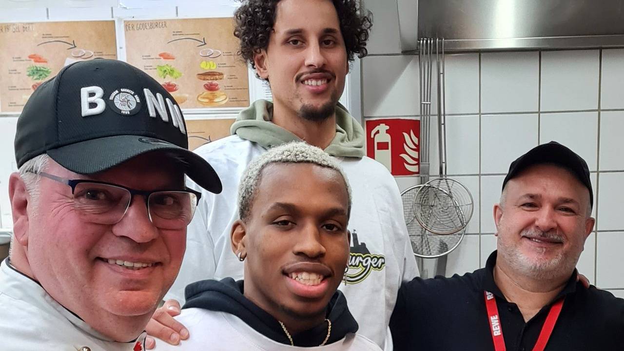 Restaurantleiter Bruno Straub, Point Guard TJ Shorts II, Center Michael Kessens und Beikoch Davut Dere-Knapp stehen in der Küche des „Godesburgers“.