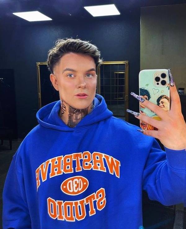 Influencer Twenty4Tim lächelt in einem blauen Pullover in die Handy-Kamera.