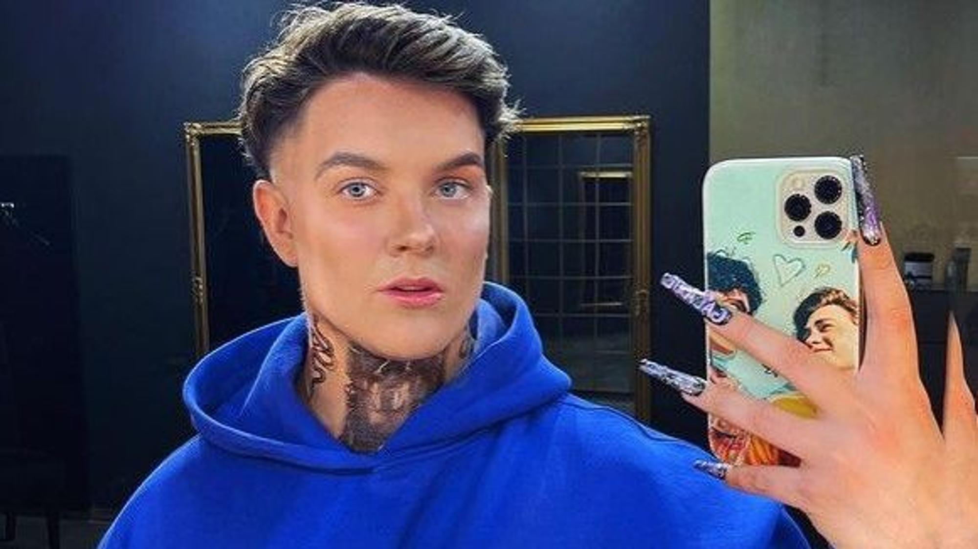 Influencer Twenty4Tim lächelt in einem blauen Pullover in die Handy-Kamera.