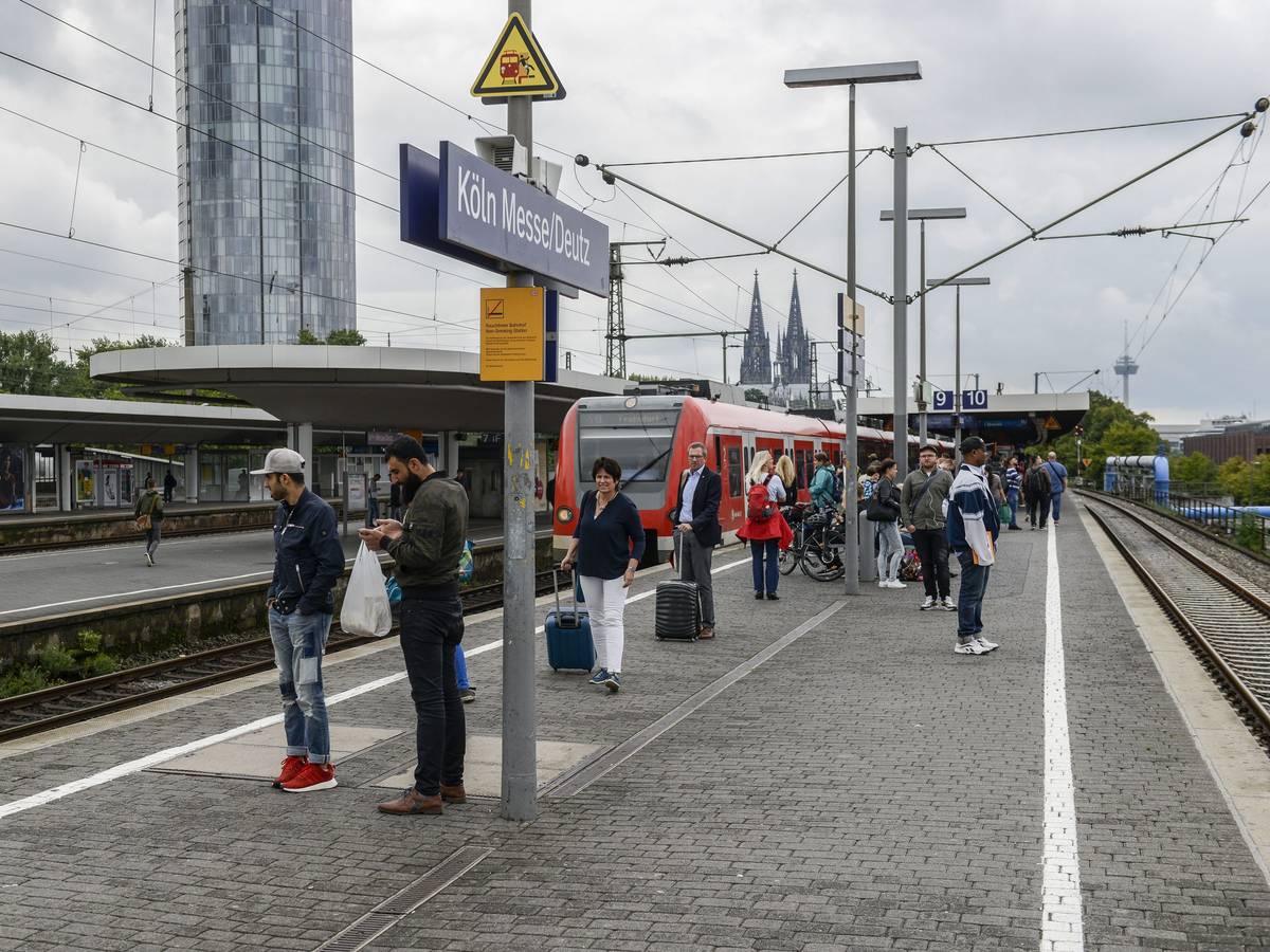 Menschen warten am Bahnsteig in Köln Messe/Deutz auf einen Zug.