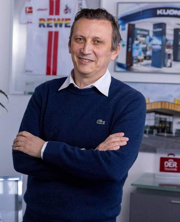 Ein Mann steht mit verschränkten Armen in einem Büro.