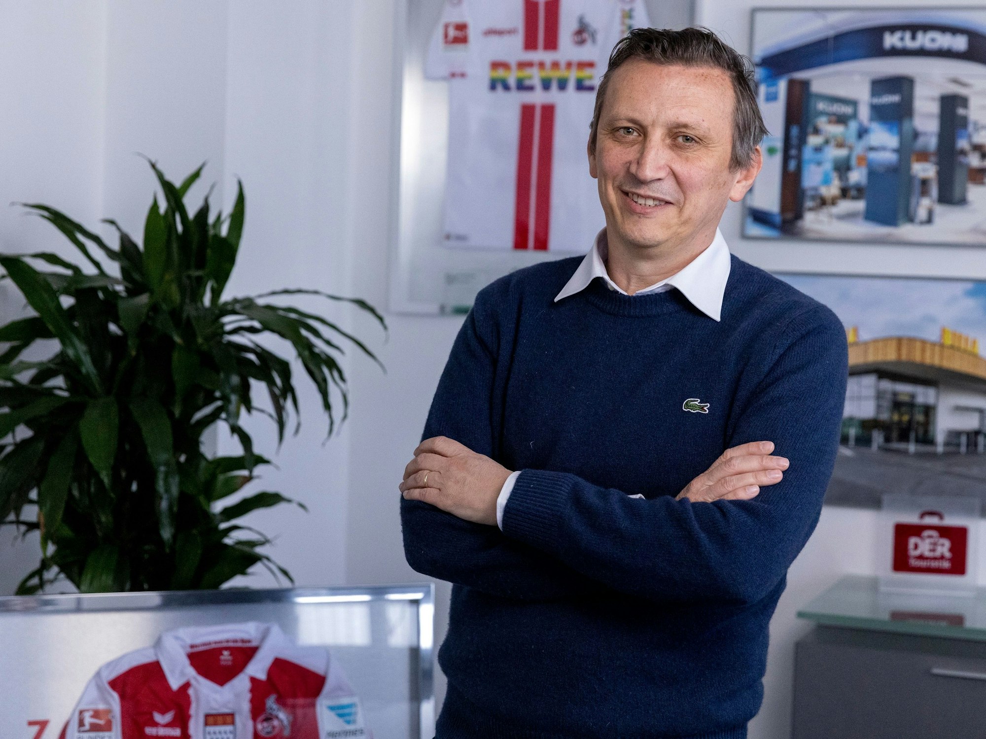 Ein Mann steht mit verschränkten Armen in einem Büro.