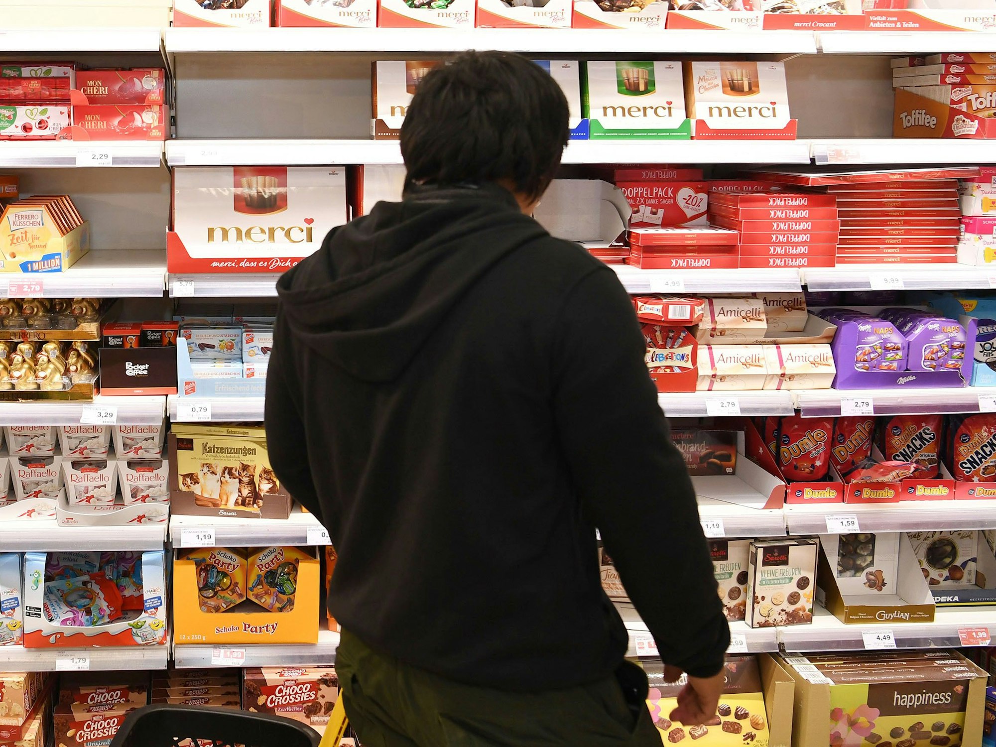 Ein Mann steht vor dem Schokoladenregal in einem Supermarkt.