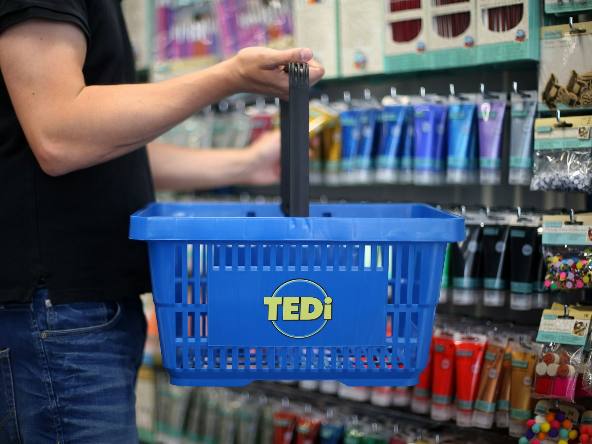 Ein Kunde in hält in einer Tedi-Filiale einen Einkaufskorb.