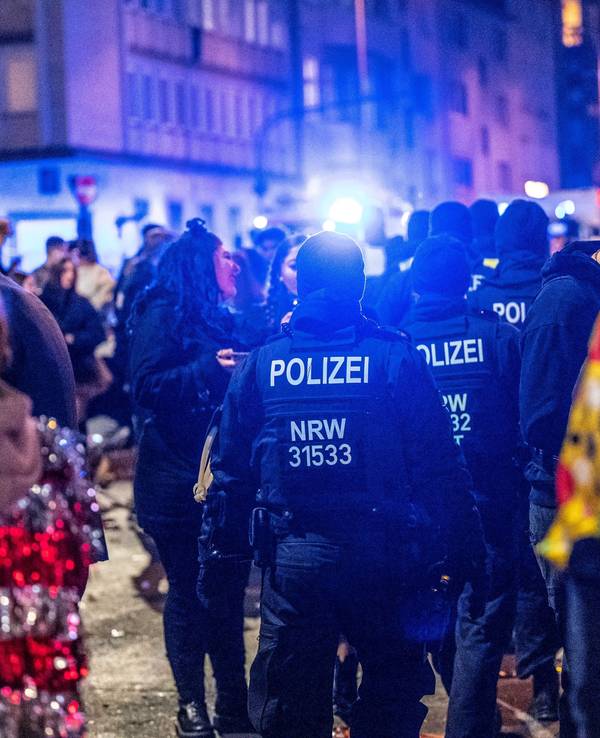 Polizeikräfte sind zwischen verkleideten Jecken unterwegs.