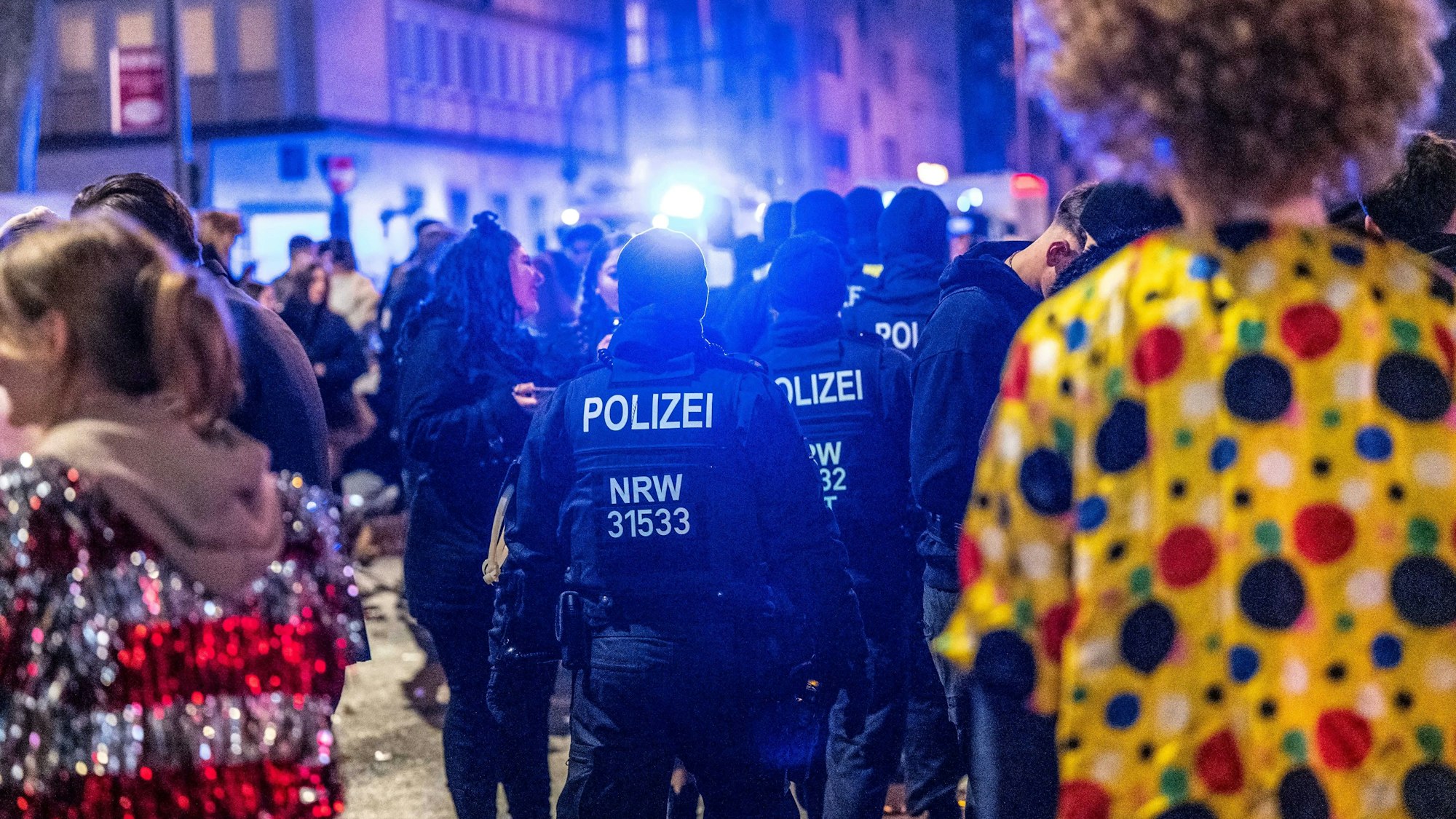Polizeikräfte sind zwischen verkleideten Jecken unterwegs.