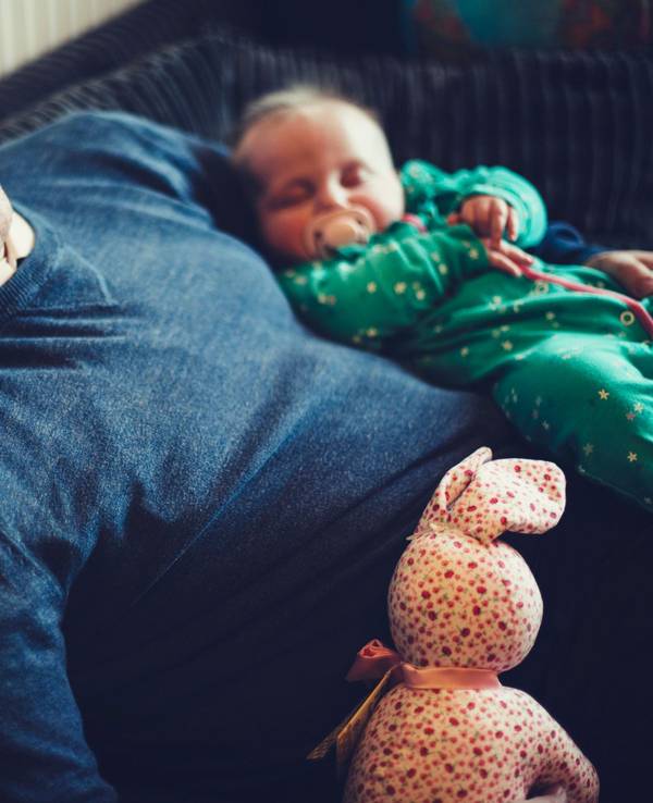 Papa und Baby sind im Sitzen auf dem Sofa eingeschlafen.