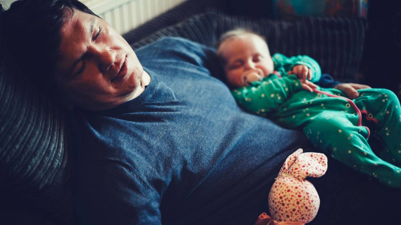 Papa und Baby sind im Sitzen auf dem Sofa eingeschlafen.