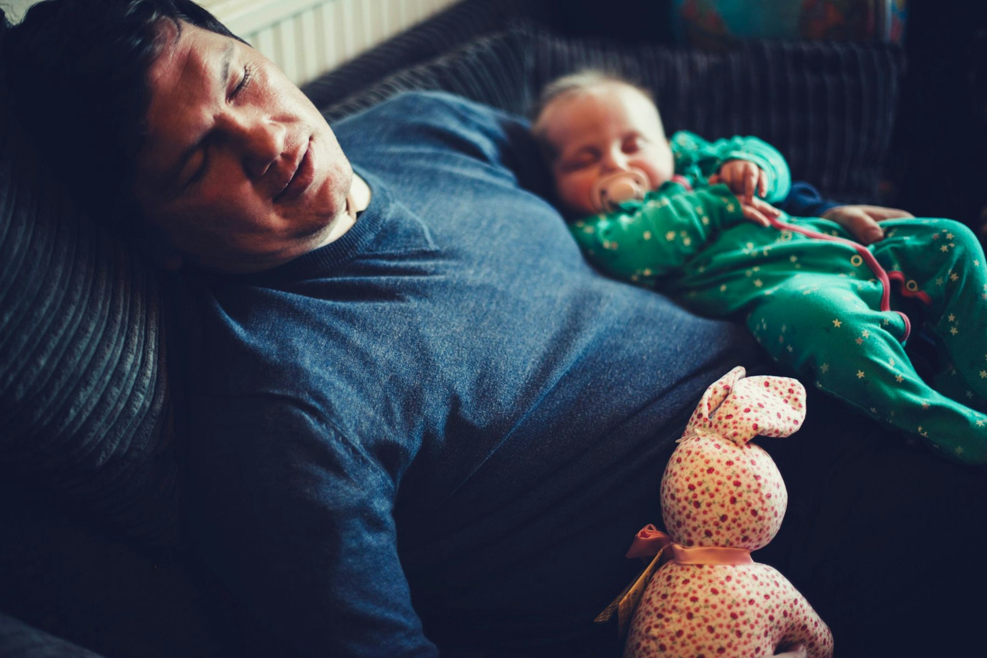 Papa und Baby sind im Sitzen auf dem Sofa eingeschlafen.