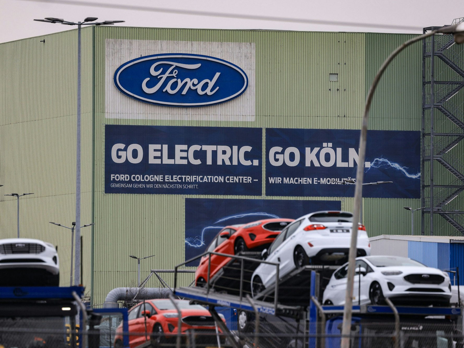 Autos stehen auf Transportfahrzeugen auf dem Werksgelände von Ford in Köln. Hier sollen in Zukunft zwei E-Modelle produziert werden.