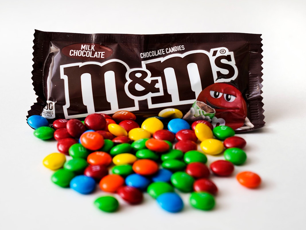 M&M's liegen vor einer Packung der Schokolinsen.